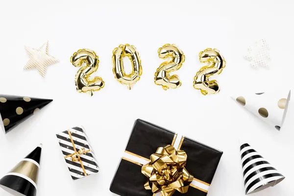 Feliz Año Nuevo 2022 tarjeta de celebración. Globos dorados numeral 2022 sobre fondo blanco. Regalos y sombreros de fiesta. —  Fotos de Stock