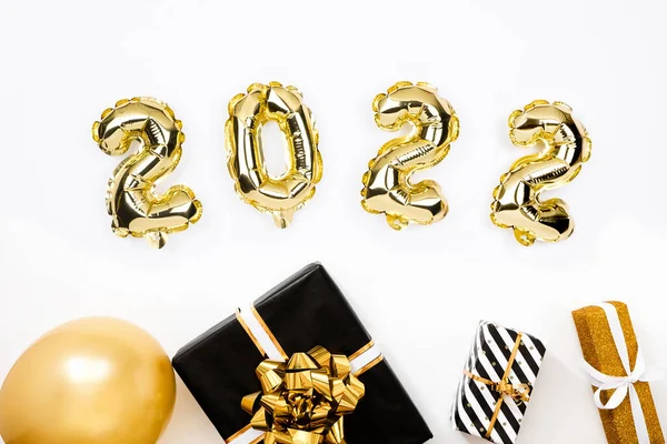 Feliz Año Nuevo 2022 tarjeta de celebración. Globos dorados numeral 2022 sobre fondo blanco. Regalos y sombreros de fiesta. —  Fotos de Stock