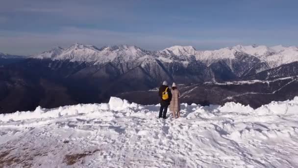 Några i snöbergen. Flygfoto över snö bergskedja landskap i Sotji under blå himmel med moln i bakgrunden. Vinterdrönarbilder — Stockvideo