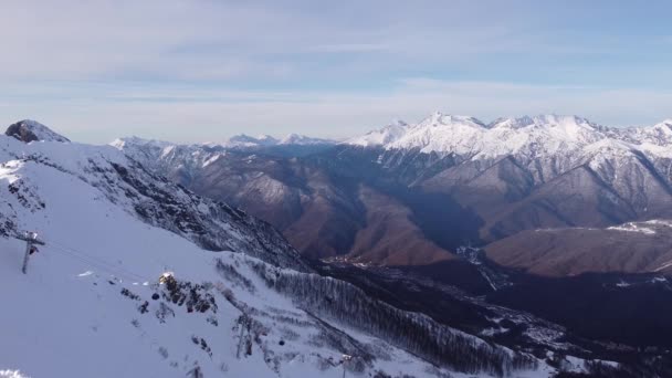 Luftaufnahme der schneebedeckten Gebirgslandschaft in Sotschi unter blauem Himmel. Winter-Drohnenaufnahmen über Gipfeln. Epische Naturpanoramen. Schönes Gebirge Winter inspirierende Landschaft — Stockvideo