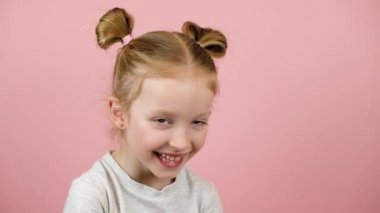 Gülümseyen ve pembe arka planda şehvet arayan komik küçük sarışın kız. Sevgi ve mutluluk. Sevgililer Günü ya da Anneler Günü konsepti