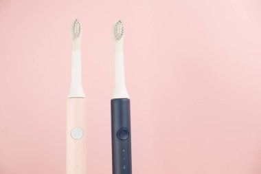 Yeni modern ultrasonik diş fırçası. Çene modeli ve pembe pastel arka planda diş bakımı malzemeleri. Ağız temizliği, diş ve diş sağlığı, sağlıklı dişler. Diş ürünleri Ultrasonik titreşim diş fırçası