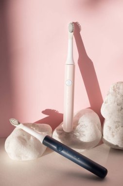 Yeni modern ultrasonik diş fırçaları. Pembe pastel arka planda beyaz taşlı diş bakımı malzemeleri. Ağız temizliği, diş sağlığı, sağlıklı dişler. Diş ürünleri Ultrasonik titreşim diş fırçası.