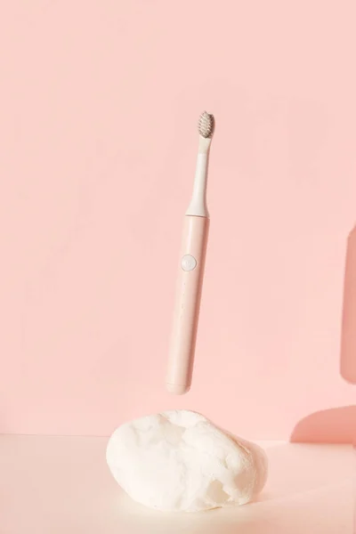 Flying modern ultrasonic toothbrush. Dental care supplies on white stone on pink pastel background. Oral hygiene, dental and gum health, healthy teeth. Dental products Wireless control. — Stock Photo, Image