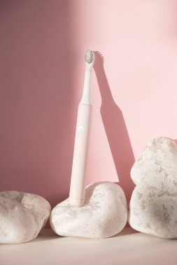 Yeni modern ultrasonik diş fırçası. Pembe pastel arka planda beyaz taşlı diş bakımı malzemeleri. Ağız temizliği, diş ve diş sağlığı, sağlıklı dişler. Diş ürünleri Ultrasonik titreşim diş fırçası.