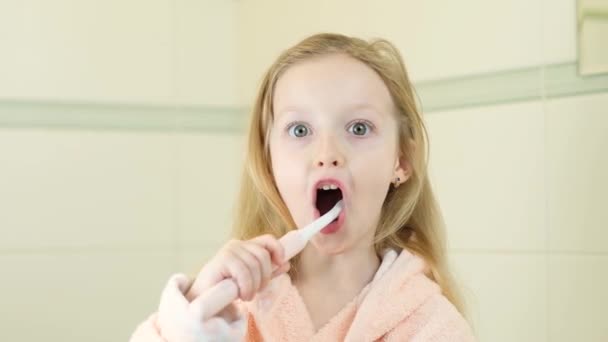 Happy smiling little girl brush teeth using ultrasonic electric toothbrush in bathroom at home. Oral hygiene, dental and gum health, healthy teeth. Daily life and routine. — Stock Video