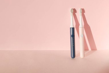 İki yeni modern ultrasonik diş fırçası. Pembe pastel arka planda diş bakımı malzemeleri. Ağız temizliği, diş ve diş sağlığı, sağlıklı dişler. Diş ürünleri Ultrasonik titreşim diş fırçası.