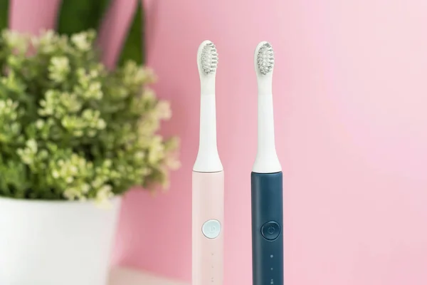 New modern ultrasonic toothbrushes. Dental care supplies with green leaves on pink pastel background. Oral hygiene, gum health, healthy teeth. Dental products Ultrasonic vibration toothbrush. — Stock Photo, Image