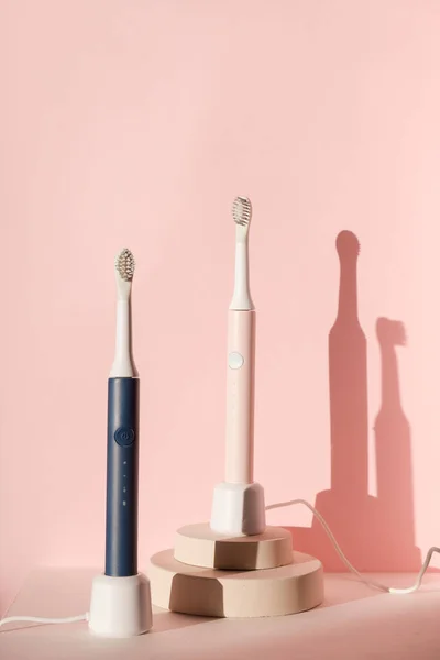 New modern ultrasonic toothbrushes. Dental care supplies on cylinder podium on pink pastel background. Oral hygiene, dental and gum health, healthy teeth. Dental products — Stock Photo, Image