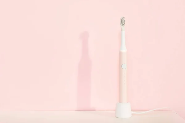 New modern ultrasonic toothbrush. Jaw model and dental care supplies on pink pastel background. Oral hygiene, dental and gum health, healthy teeth. Dental products Ultrasonic vibration toothbrush. — Stock Photo, Image