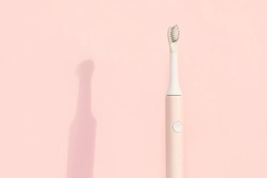 Yeni modern ultrasonik diş fırçası. Çene modeli ve pembe pastel arka planda diş bakımı malzemeleri. Ağız temizliği, diş ve diş sağlığı, sağlıklı dişler. Diş ürünleri Ultrasonik titreşim diş fırçası.