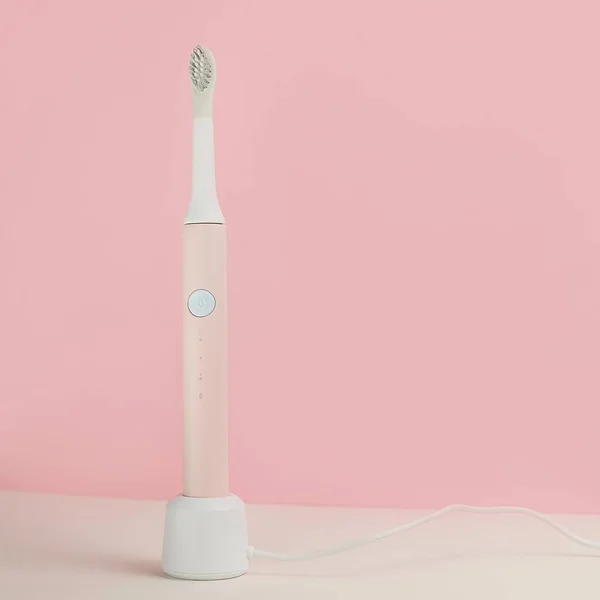 New modern ultrasonic toothbrushes. Dental care supplies with green leaves on pink pastel background. Oral hygiene, gum health, healthy teeth. Dental products Ultrasonic vibration toothbrush. — Stock Photo, Image