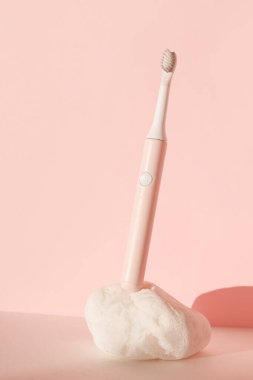 Yeni modern ultrasonik diş fırçası. Pembe pastel arka planda beyaz taş üzerinde diş bakımı malzemeleri. Ağız temizliği, diş ve diş sağlığı, sağlıklı dişler. Diş ürünleri Ultrasonik titreşim diş fırçası.