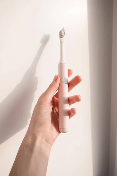 New modern ultrasonic toothbrush in woman hand. Jaw model and dental care supplies. Oral hygiene, dental and gum health, healthy teeth. Dental products Ultrasonic vibration toothbrush. — Stock Photo, Image
