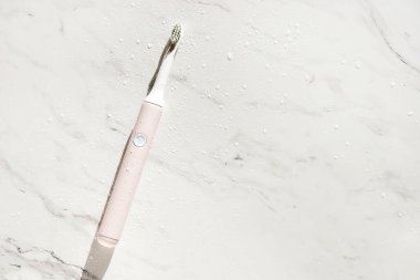 Yeni modern ultrasonik diş fırçası mermer zemin üzerinde su damlaları var. Ağız temizliği, diş ve diş sağlığı, sağlıklı dişler. Diş ürünleri Ultrasonik titreşim diş fırçası.