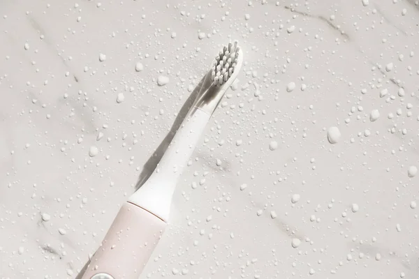Nova escova de dentes ultra-sônica moderna com salpicos e gotas de água no fundo de mármore. Higiene oral, saúde dentária e gengival, dentes saudáveis. Dental products Escova de dentes de vibração ultra-sônica. — Fotografia de Stock
