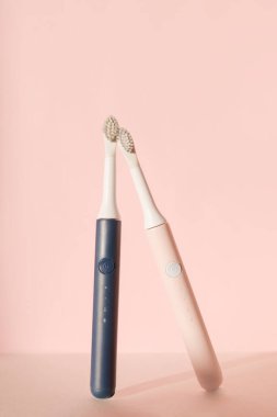 İki yeni modern ultrasonik diş fırçası. Pembe pastel arka planda diş bakımı malzemeleri. Ağız temizliği, diş ve diş sağlığı, sağlıklı dişler. Diş ürünleri Ultrasonik titreşim diş fırçası.