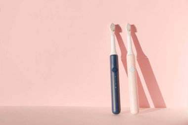 İki yeni modern ultrasonik diş fırçası. Pembe pastel arka planda diş bakımı malzemeleri. Ağız temizliği, diş ve diş sağlığı, sağlıklı dişler. Diş ürünleri Ultrasonik titreşim diş fırçası.