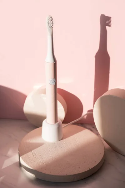 New modern ultrasonic toothbrush. Dental care supplies on cylinder podium on pink pastel background. Oral hygiene, dental and gum health, healthy teeth. Dental products — Stock Photo, Image