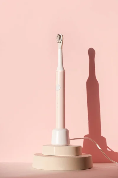 New modern ultrasonic toothbrush. Dental care supplies on cylinder podium on pink pastel background. Oral hygiene, dental and gum health, healthy teeth. Dental products — Stock Photo, Image