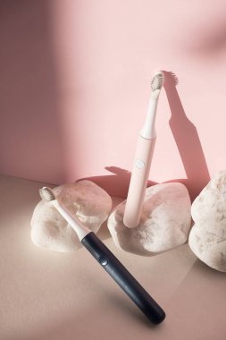 Yeni modern ultrasonik diş fırçaları. Pembe pastel arka planda beyaz taşlı diş bakımı malzemeleri. Ağız temizliği, diş sağlığı, sağlıklı dişler. Diş ürünleri Ultrasonik titreşim diş fırçası.