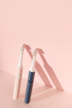 İki yeni modern ultrasonik diş fırçası. Pembe pastel arka planda diş bakımı malzemeleri. Ağız temizliği, diş ve diş sağlığı, sağlıklı dişler. Diş ürünleri Ultrasonik titreşim diş fırçası.