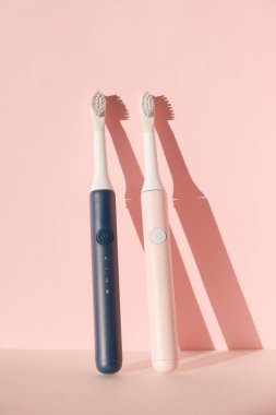 İki yeni modern ultrasonik diş fırçası. Pembe pastel arka planda diş bakımı malzemeleri. Ağız temizliği, diş ve diş sağlığı, sağlıklı dişler. Diş ürünleri Ultrasonik titreşim diş fırçası.