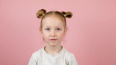 Gülümseyen ve pembe arka planda altın paskalya yumurtalarıyla oynayan komik sarışın kız. Mutlu Paskalyalar