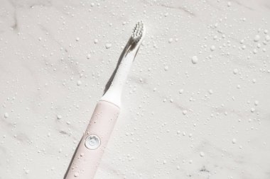 Yeni modern ultrasonik diş fırçası mermer zemin üzerinde su damlaları var. Ağız temizliği, diş ve diş sağlığı, sağlıklı dişler. Diş ürünleri Ultrasonik titreşim diş fırçası.