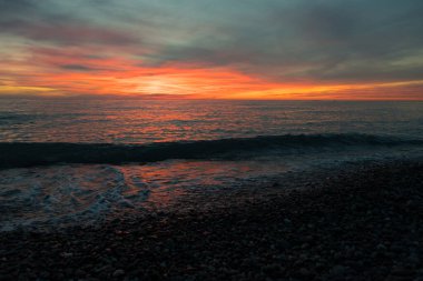 Ocean beach sunrise and dramatic colorful sky clouds. Dramatic sea sunrise. Burning sky and shining golden waves