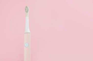 Yeni modern ultrasonik diş fırçası. Çene modeli ve pembe pastel arka planda diş bakımı malzemeleri. Ağız temizliği, diş ve diş sağlığı, sağlıklı dişler. Diş ürünleri Ultrasonik titreşim diş fırçası.