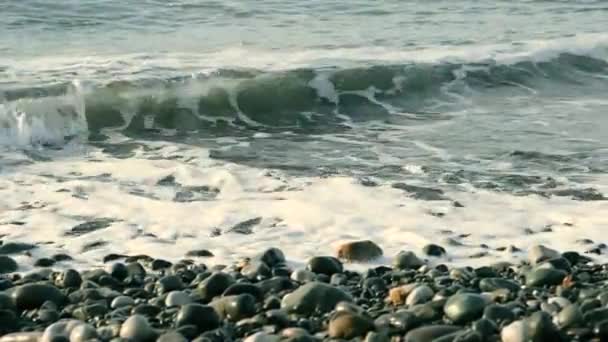 Deniz Dalgaları Sahilde Çakıl Taşları. Sahilde çakıl taşlarını yıkayan bir deniz dalgasının yakın çekim görüntüleri. Çakıl taşı renkli kıyı şeridi, yatay. Dalgalar çakıl taşı plajına ulaşıyor. — Stok video