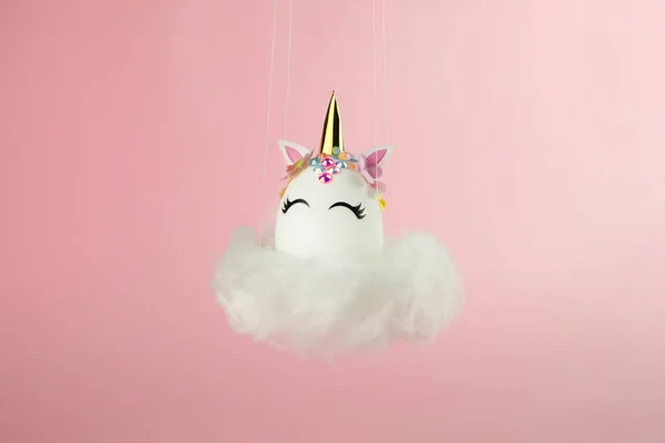 Easter unicorn egg flying on cloud on pastel pink background. Happy easter banner. Kids activity inspiration. Greeting card or poster. Copy space for text. Levitation egg — Foto Stock