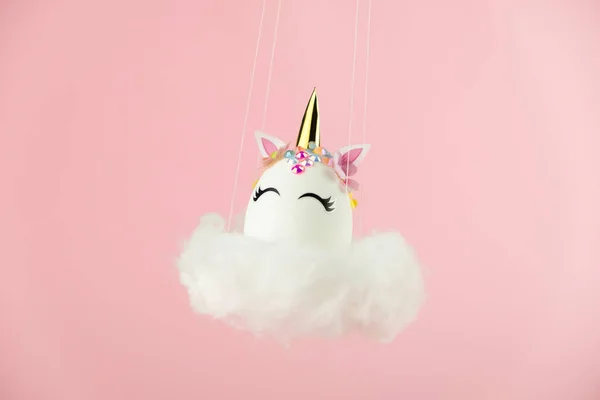 Easter unicorn egg flying on cloud on pastel pink background. Happy easter banner. Kids activity inspiration. Greeting card or poster. Copy space for text. Levitation egg — Foto Stock