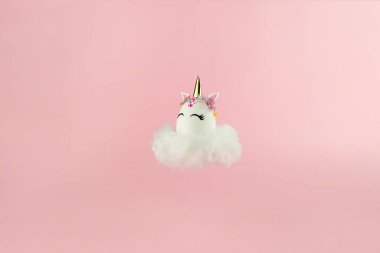 Easter unicorn egg flying on cloud on pastel pink background. Happy easter banner. Kids activity inspiration. Greeting card or poster. Copy space for text. Levitation egg