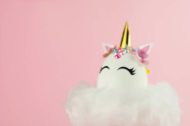 Easter unicorn egg flying on cloud on pastel pink background. Happy easter banner. Kids activity inspiration. Greeting card or poster. Copy space for text. Levitation egg