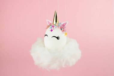 Easter unicorn egg flying on cloud on pastel pink background. Happy easter banner. Kids activity inspiration. Greeting card or poster. Copy space for text. Levitation egg
