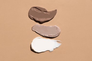 White cream texture on a pastel beige background. Cosmetic mask balm gel. Smears of foundation for the face