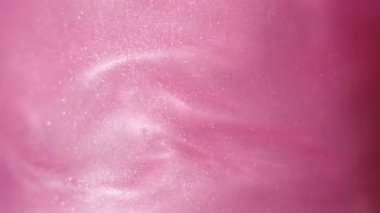 Glittering abstract pink background. Color fluid is swirling in beautiful silver clouds. Glitter dust is moving slowly in water. Amazing abstract texture background.