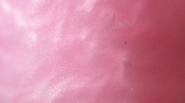 Glittering abstract pink background. Color fluid is swirling in beautiful silver clouds. Glitter dust is moving slowly in water. Amazing abstract texture background.