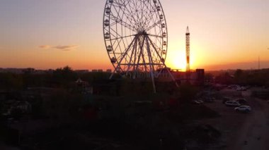 Ferris wheel against a sunset sky. Twilight waves against classic illuminated ferris wheel, amusement park for tourists. Summertime symbol.
