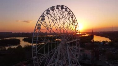 Ferris wheel against a sunset sky. Twilight waves against classic illuminated ferris wheel, amusement park for tourists. Summertime symbol.