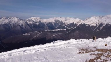 Kar dağlarında bir çift. Soçi 'deki kar dağı manzarasının mavi gökyüzünün altında arka planda bulutlar var. Kış İHA görüntüleri