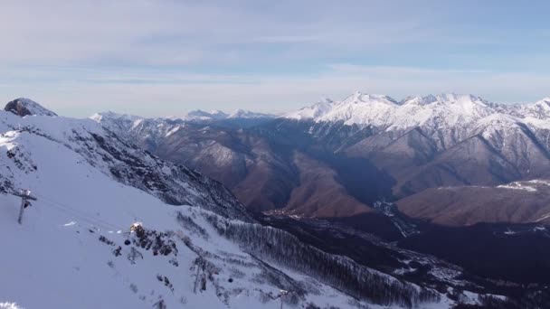 Flygfoto över snö bergskedja landskap i Sotji under blå himmel. Vinterdrönarbilder över toppar. Episk Panorama Natur. Vacker bergskedja Vinterinspirerande landskap — Stockvideo