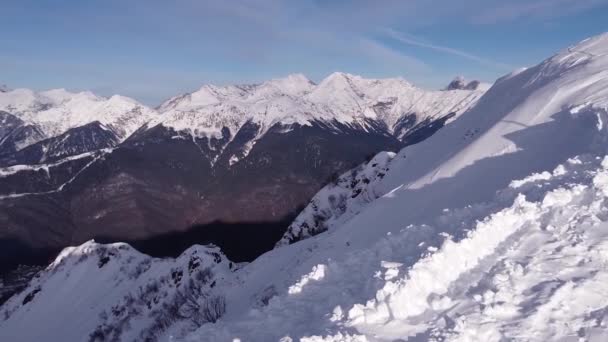 Letecký pohled na zasněženou horskou krajinu v Soči pod modrou oblohou. Záznam ze zimních dronů nad vrcholky. Epic Panorama Nature. Krásné pohoří Zima Inspirující krajina — Stock video