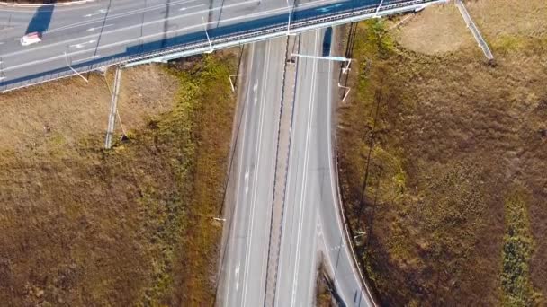Letecký bezpilotní pohled na dálniční víceúrovňovou křižovatku s jedoucími vozy. Film drone shot létání nad zemí silnici s podzimními stromy při západu slunce — Stock video