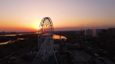 Ferris wheel against a sunset sky. Twilight waves against classic illuminated ferris wheel, amusement park for tourists. Summertime symbol.
