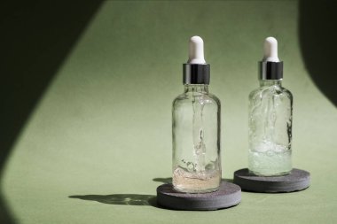 Dropper glass Bottle Mock-Up on green background. Body treatment and spa. Natural beauty products. Eco cream, serum, skin care blank bottle. Anti-cellulite massage oil. Oily cosmetic pipette.