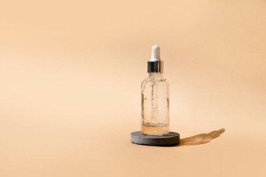 Dropper glass Bottle Mock-Up on beige cosmetic podium. Body treatment and spa. Natural beauty products. Eco cream, serum, skin care blank bottle. Anti-cellulite massage oil. Oily cosmetic pipette.