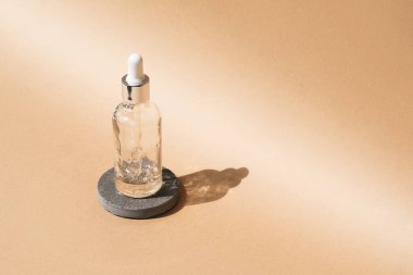 Dropper glass Bottle Mock-Up on beige cosmetic podium. Body treatment and spa. Natural beauty products. Eco cream, serum, skin care blank bottle. Anti-cellulite massage oil. Oily cosmetic pipette.